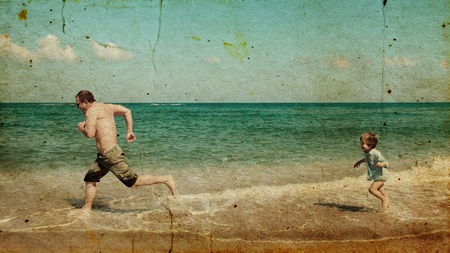 Father and son looking at a white sail in the sea. Photo in old image style.の写真素材