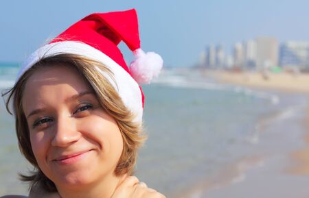 Christmas at sea. Girl in Santa hat on the beach.の写真素材