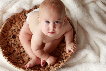 7-month-old beautiful child with blue eyes on a white blanket