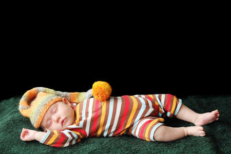 baby sleeps in a hat on a blanketの写真素材