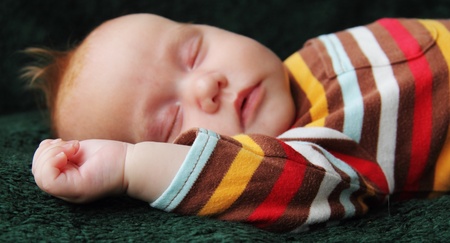 baby sleeps in a hat on a blanketの写真素材