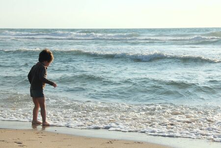 child at the sea on sunset colorsの写真素材