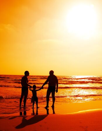 child with his father and grandfather watching sunsetの写真素材