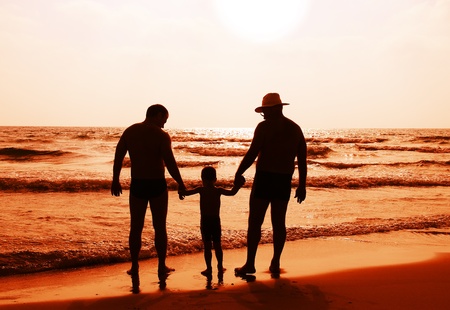 child with his father and grandfather watching sunsetの写真素材