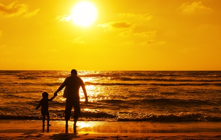 silhouettes of father and son on sunset の写真素材