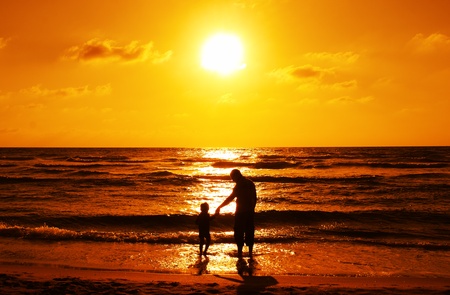 silhouettes of father and son on sunset の写真素材