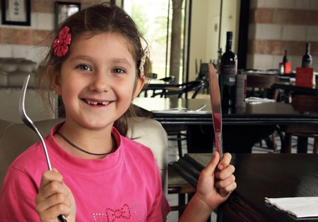 pretty funny girl in a cafe, holding a knife and fork の写真素材