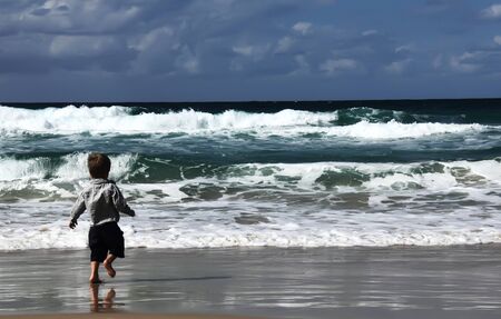 3-year-old looks at the sea. Autumn sea, strong waves, sharp colors.の写真素材