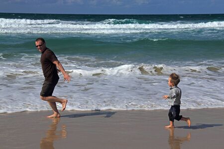 Dad and son playing on the sea  Autumn sea, strong waves, sharp colors の写真素材