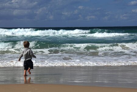 3-year-old looks at the sea  Autumn sea, strong waves, sharp colors の写真素材