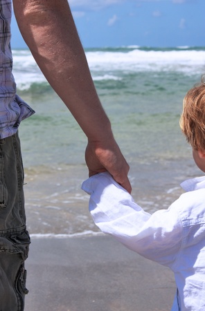 father holds the hand of his 2-year-old sonの写真素材
