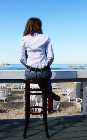 A girl sits alone in a cafe and looks at seaの写真素材