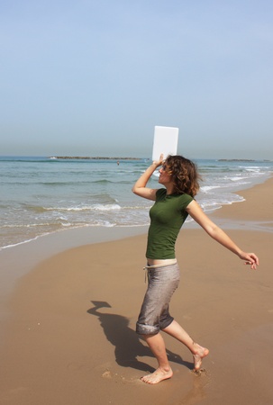 girl wants to throw in the sea her white small laptopの写真素材