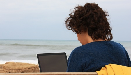 The girl sitting next to the sea and worksの写真素材