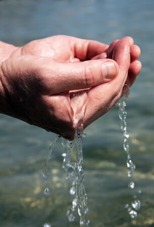 man scoops up the water with his handsの写真素材