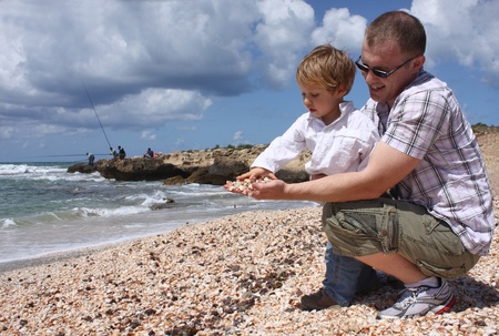 Father and son throwing shells into the sea