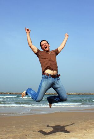 happy young man is jumping on the beachの写真素材