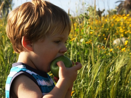 child is walking and eating an appleの写真素材