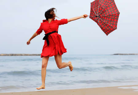 Beautiful girl in red dress on the winter beachの写真素材