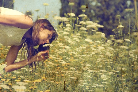 Beautiful girl smells spring flowers  Photo in old color image style の写真素材