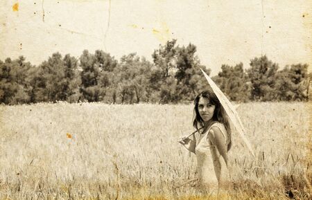 Young woman in the field. Photo in old color image style.の写真素材