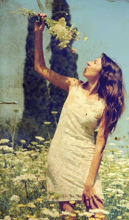 Beautiful girl smells spring flowers  Photo in old color image style の写真素材
