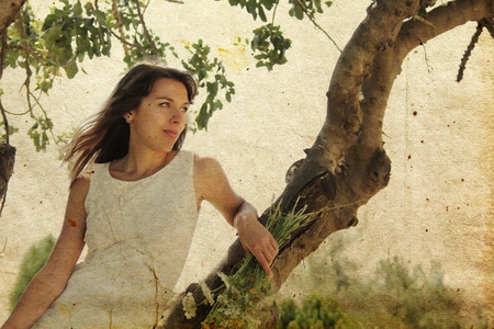 Beautiful girl in white dress sitting on the tree  Photo in old image style の写真素材