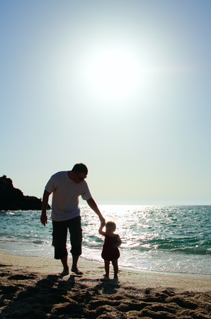 father and daughter playing on the beach at sunsetの写真素材