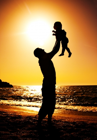 father and daughter playing on the beach at sunsetの写真素材