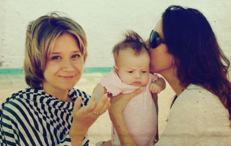 two beautiful girls with a baby on the beachの写真素材