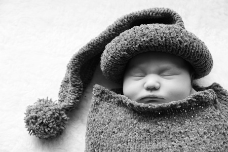 newborn in a knitted cocoon and hatの写真素材