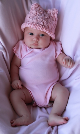 Beautiful month-old girl in a pink hat and a pink body.の写真素材