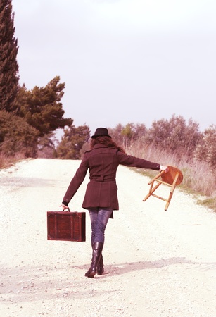 Girl holding suitcase and stoolの写真素材
