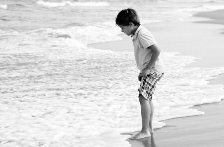 7 years old kid coming to the water's edge, sunset  colorsの写真素材
