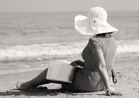 young girl in white hat and red dress on the beachの写真素材