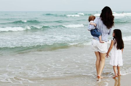 Mother with two daughters on the beachの写真素材