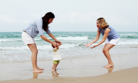 two beautiful girls with a baby on the beachの写真素材