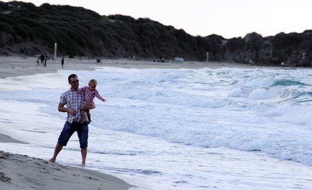 father and daughter playing together on the beach at sunsetの写真素材