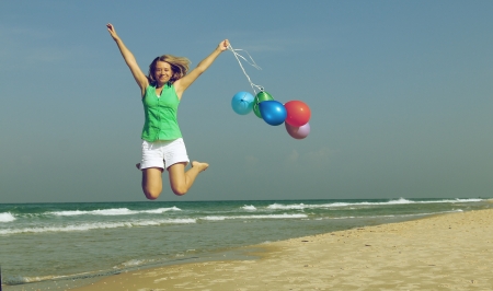 Beautiful girl with a balloons on the beach. Old style colours.の写真素材