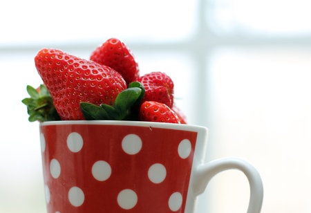 Strawberries in cup near the windowの写真素材