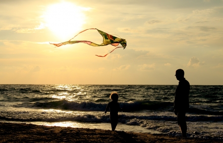  father and daughter flying kite at beachの写真素材