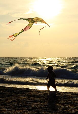 Kid playing with kite on the seaの写真素材