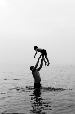 father and son swimming in the sea at sunsetの写真素材
