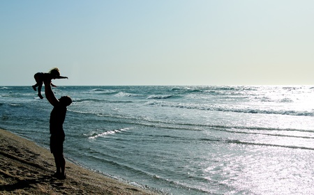 father with kid on the beach at sunsetの写真素材