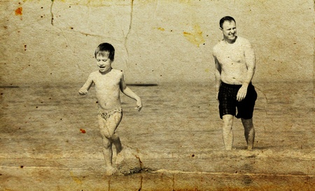 father and son going to swim in the sea. Photo in old image style.の写真素材