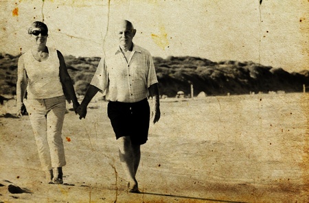 Happy senior couple walking together on a beach  Photo in old image style の写真素材