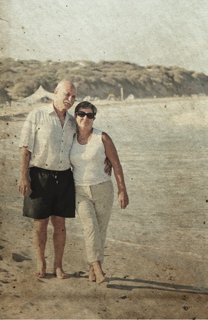 Happy senior couple walking together on a beach  Photo in old image style の写真素材