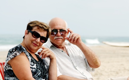 Portrait of happy senior couple sitting together on a beachの写真素材