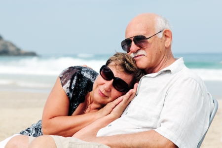 Portrait of happy senior couple sitting together on a beachの写真素材