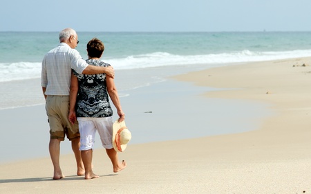 Happy senior couple walking together on a beachの写真素材